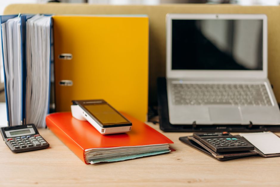 Accounting desk with binders, folders, a laptop and calculators
